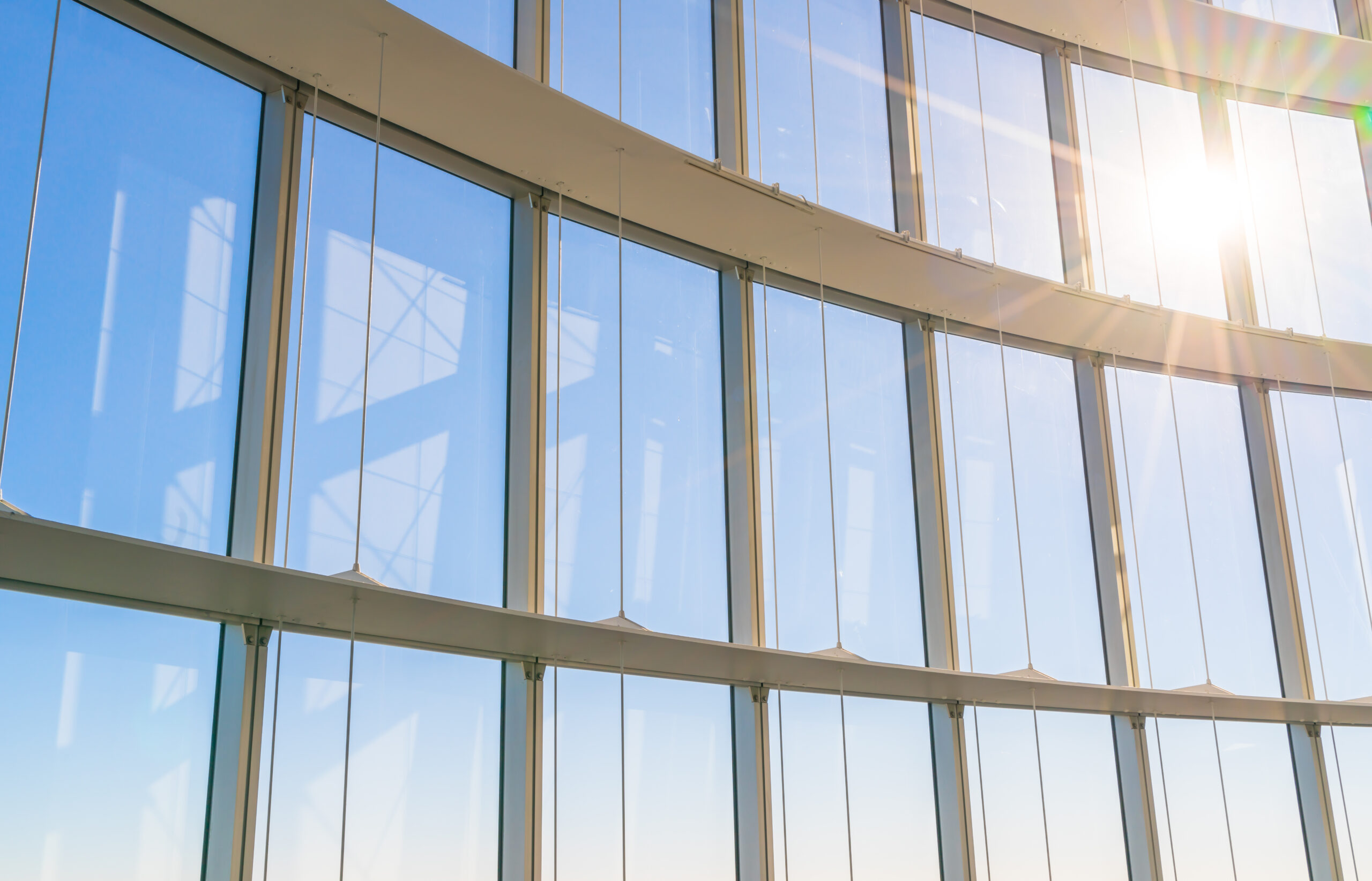 Large custom window, installed according to the project’s needs, showcasing a blue sky and the reflection of the Sun.