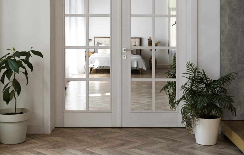 White door leading into a bright room, representing the comfort of having a protected home with well-installed doors and windows.