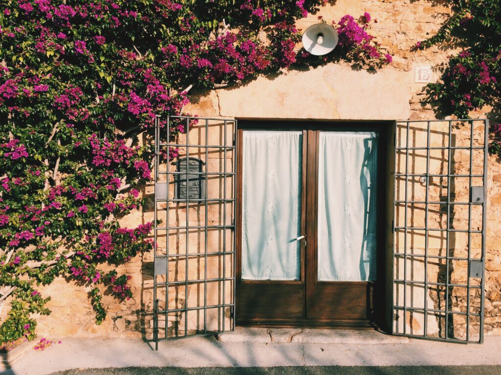 Hinged French patio door closed and surrounded by plants and flowers, showing the importance of having doors and windows installed by a trusted company.