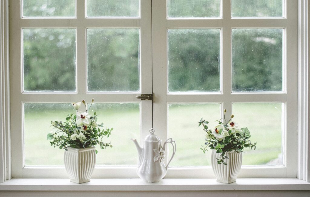 White teapot and flower vases on the sill of a specialty window, illustrating the importance of hiring specialized door and window installation services.