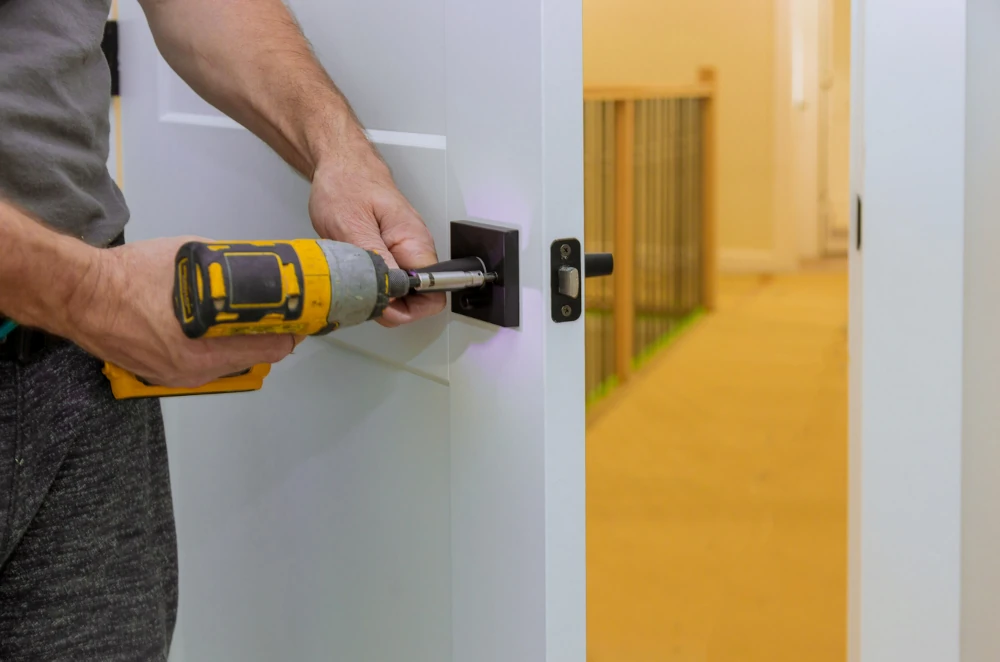 A man installing a door lock, representing the importance of partnering with the right construction subcontractors