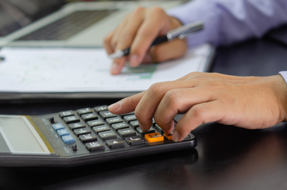 A businessman’s hand pressing on a calculator, representing the importance of budget transparency for installation of door and window.