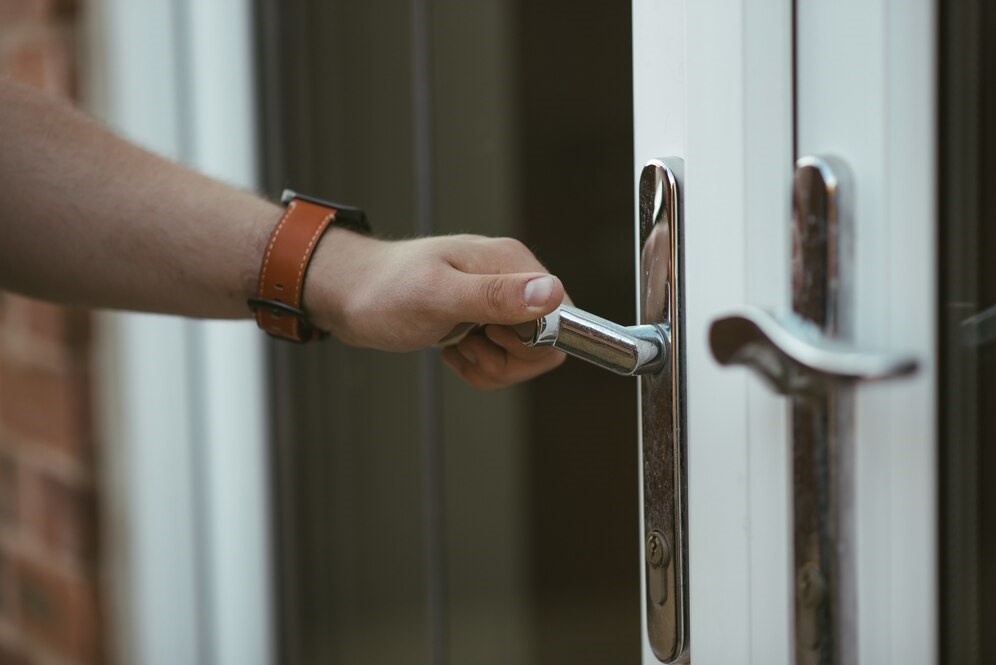 A person holding a handle and opening a door installed with soundproofing material.