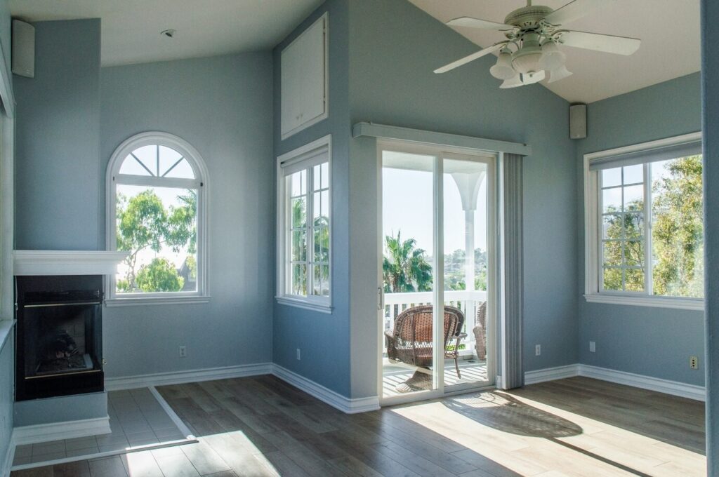 A modern living room interior with blue walls and white-framed windows, showcasing the completed renovation after the owner obtained permission to change window to door.