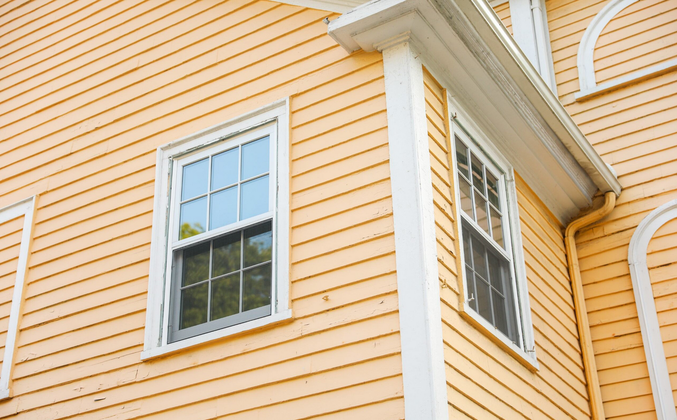 A yellow house with white windows, representing the importance of a hassle-free home renovation.