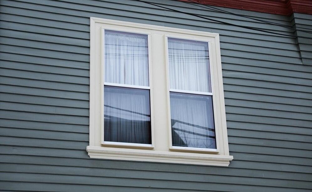 Window of a light blue American house, representing the importance of a hassle-free home renovation.