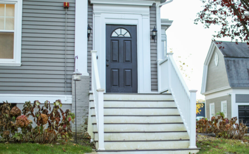 American house with a dark gray door, representing the importance of selecting customized entrance doors that reflect your style and vision.