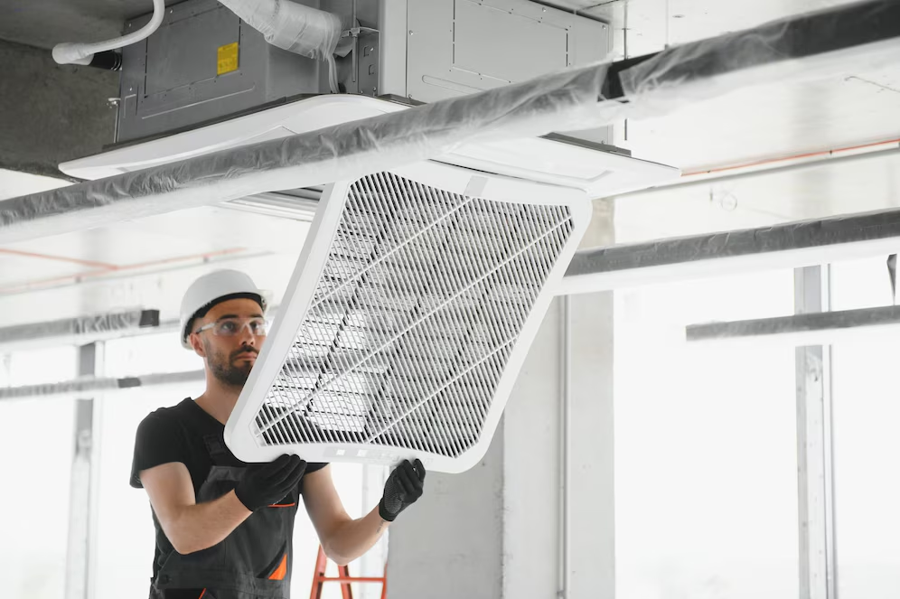 Technician fixing the HVAC system, representing the importance of investing in energy-efficient commercial windows.