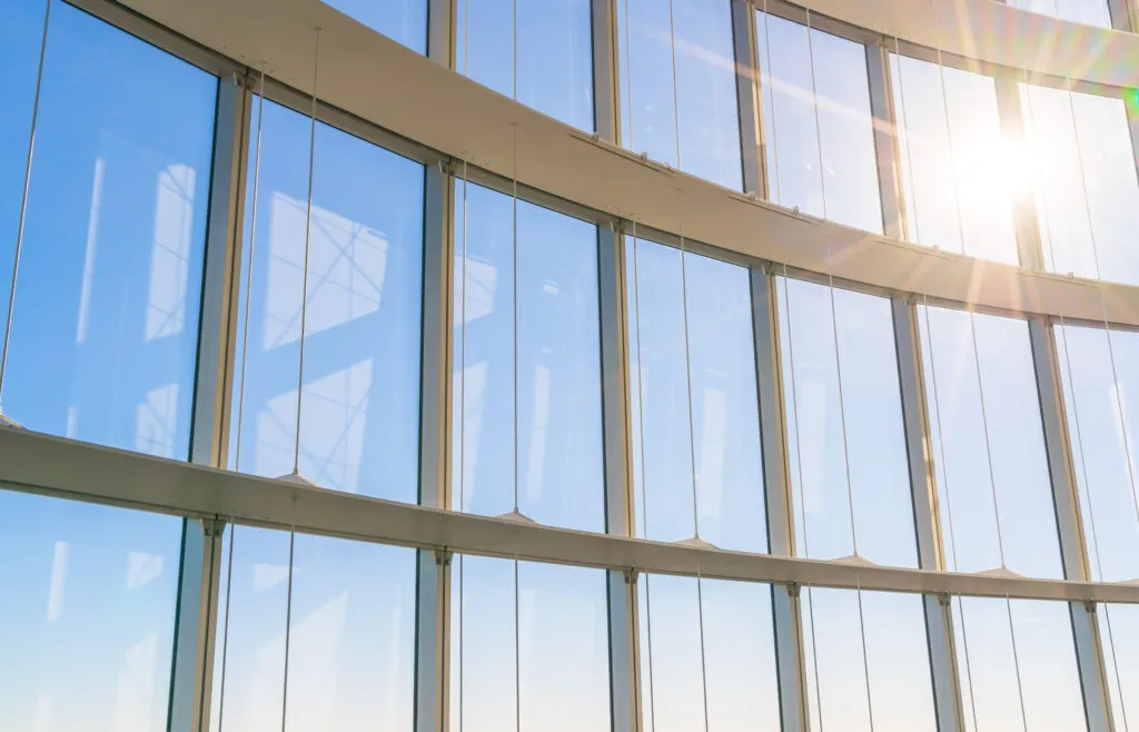 Large custom window, installed according to the project’s needs, showcasing a blue sky and the reflection of the Sun.