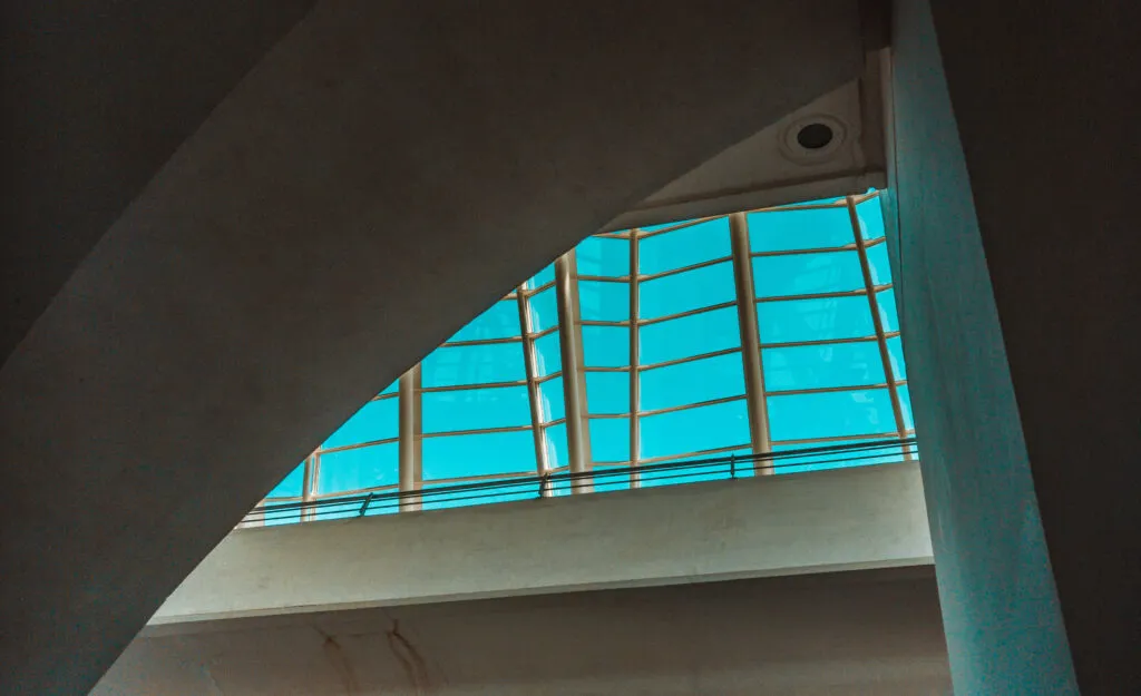 Blue sky seen through a custom window with a unique and innovative design, installed in a concrete building.