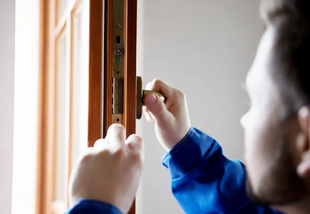 Close-up of a man holding the handle of a custom wooden door or window in a house.
