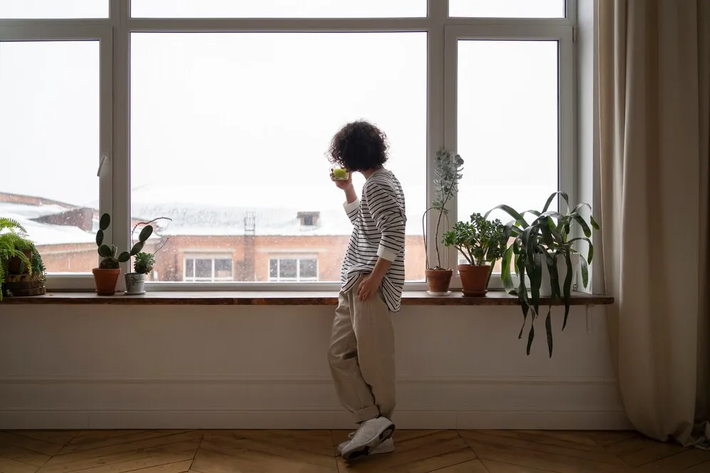 Man enjoying a cup of tea near a window after a renovation to maximize natural light.