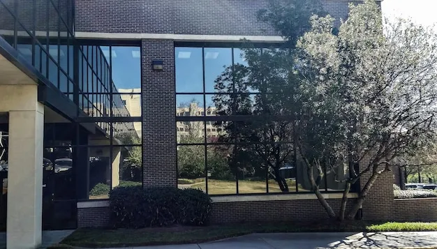 Glass window reflecting a tree on the building's outside space, representing the privacy of high-quality commercial windows and doors.