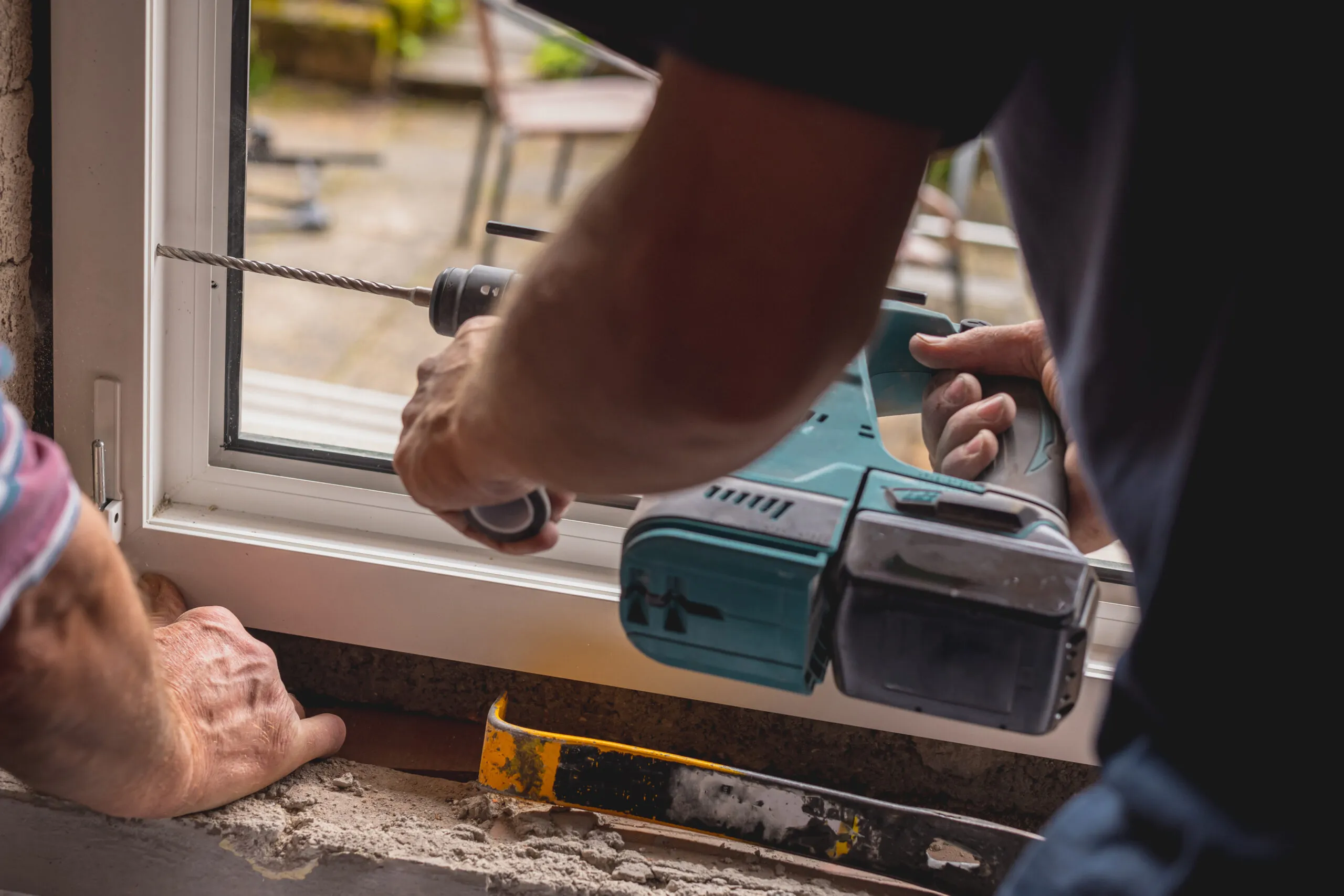Two men repairing a window, representing the importance of adopting measures to prevent window and door installation challenges.