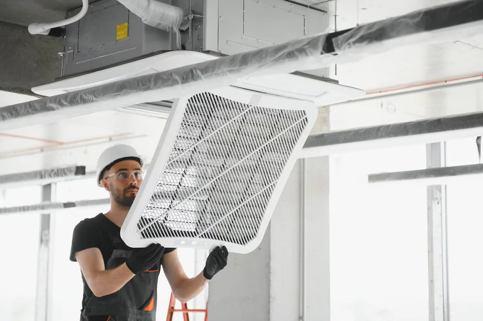 Technician fixing the HVAC system, representing the importance of investing in energy-efficient commercial windows.
